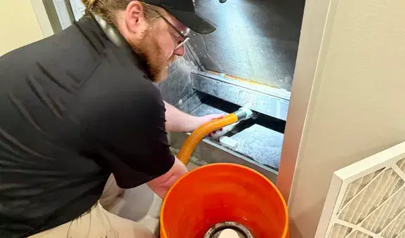 Austin servicing an HVAC unit in a downtown Austin condo, vacuuming the condensate drain